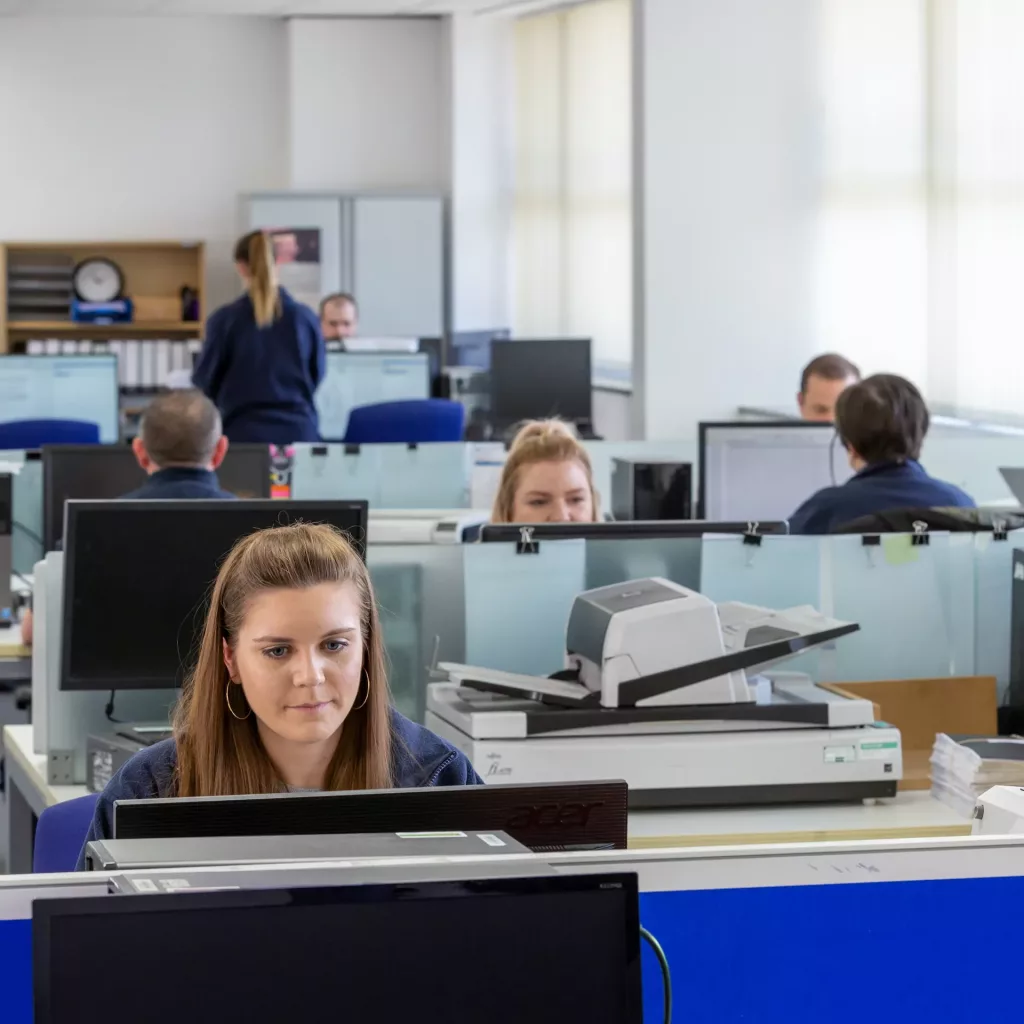 Office staff working on computers with document scanners